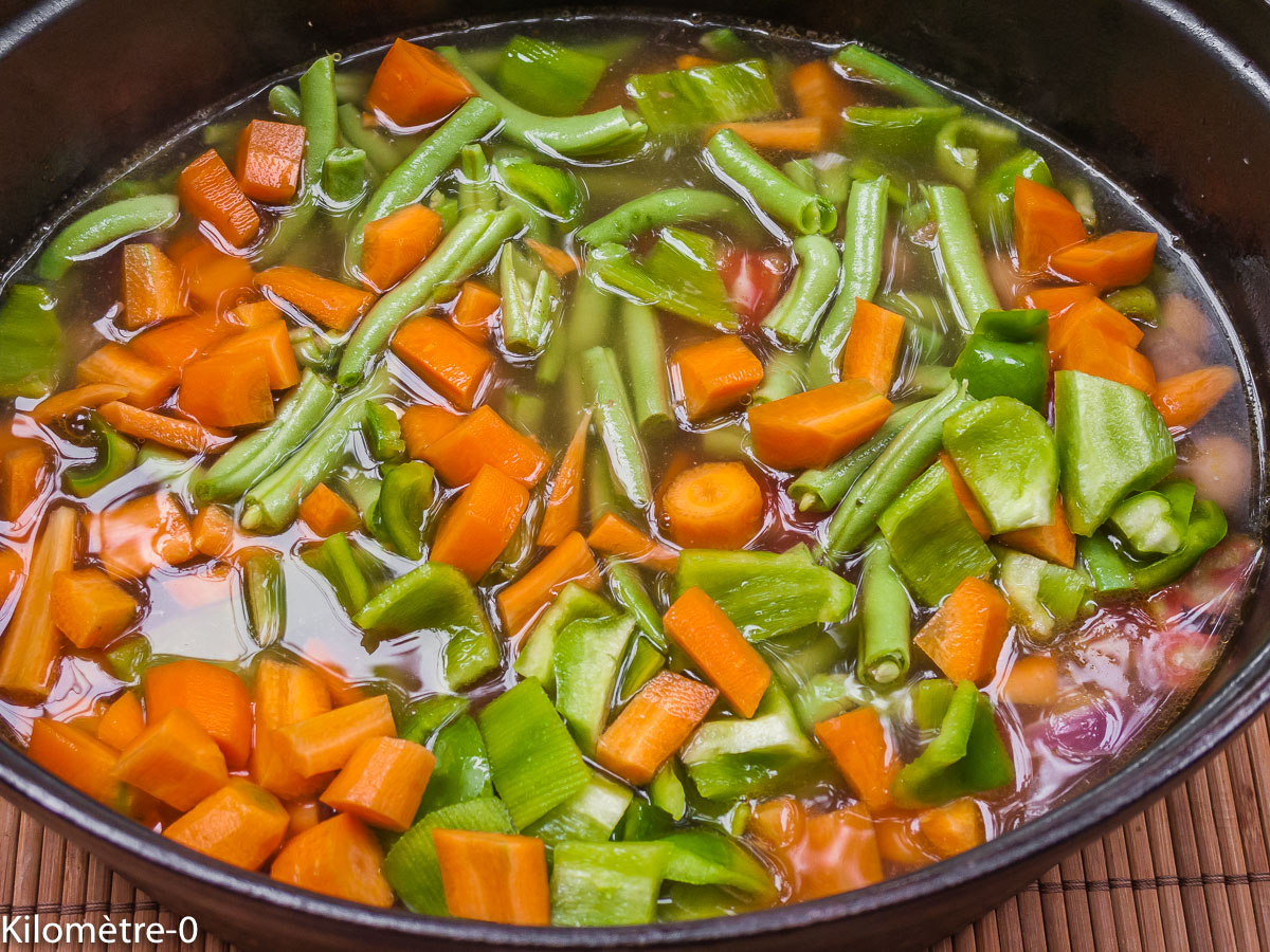 Riz jollof : étape 3 — Ajoutez le bouillon de volaille sur le poulet et l'oignon et portez-le à ébullition.